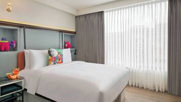 Een moderne hotelkamer met een groot bed, een nachtkastje, een lamp en een raam met gordijnen.