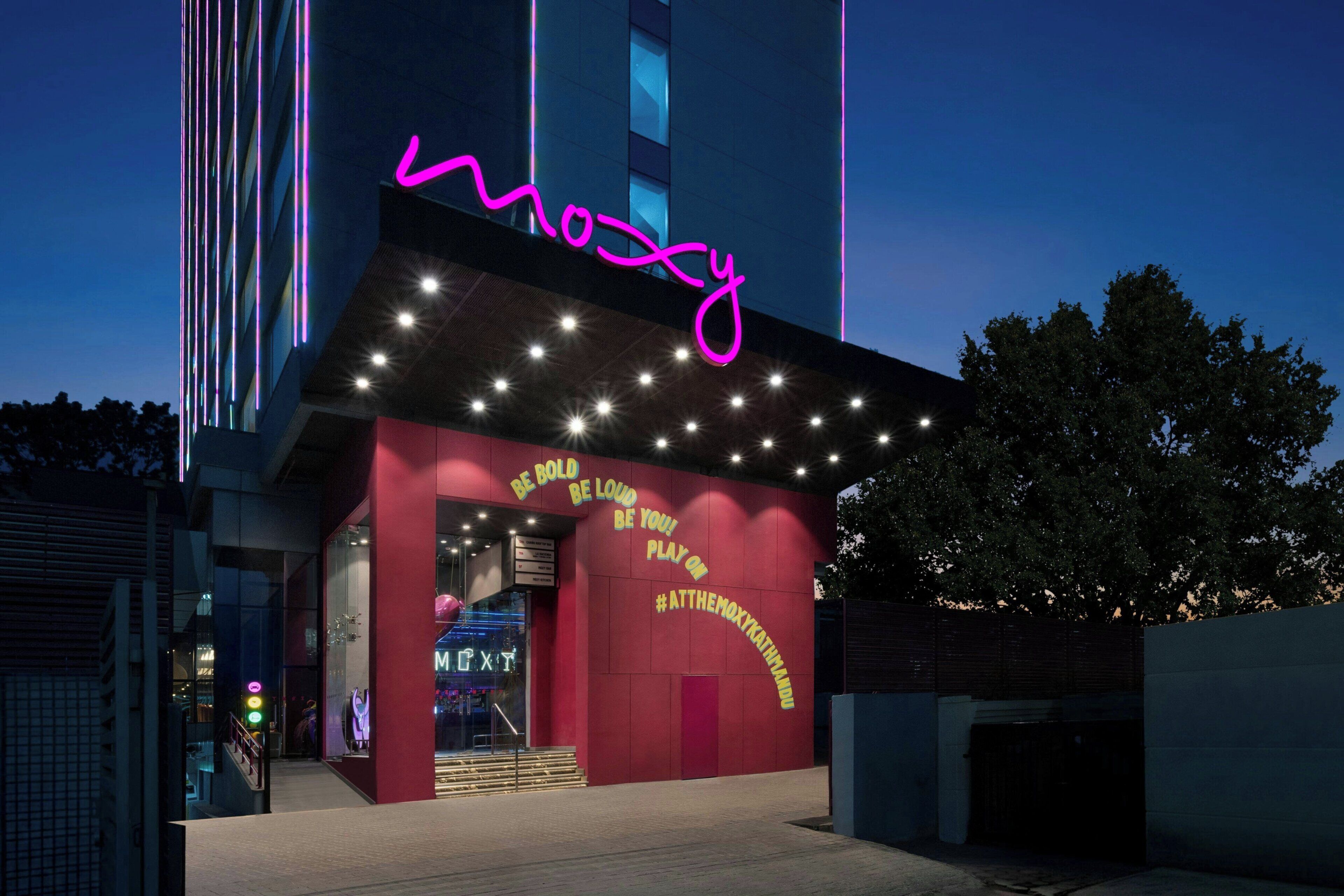 Um edifício com um letreiro de neon que diz 'mozy' e um slogan na fachada.