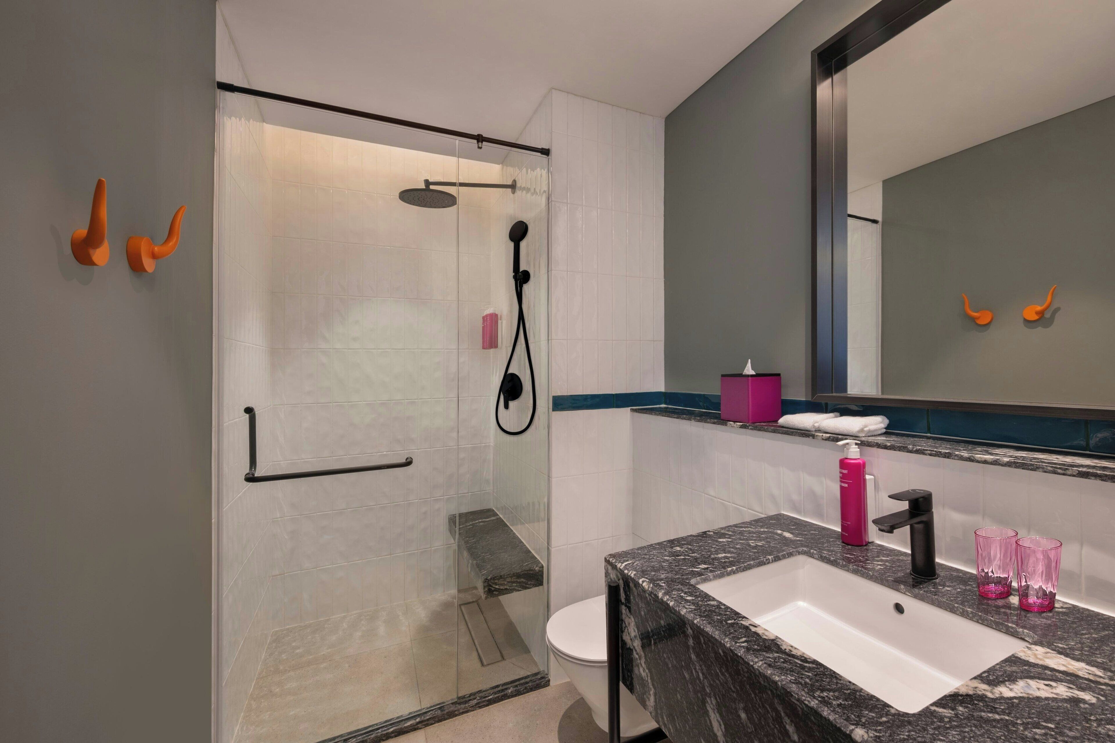 A modern bathroom with a glass-enclosed shower, a white sink with a black faucet, and a mirror with a black frame.