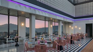 A rooftop restaurant with a city view, large windows, and modern furnishings. - Moxy Kathmandu (Kathmandu)