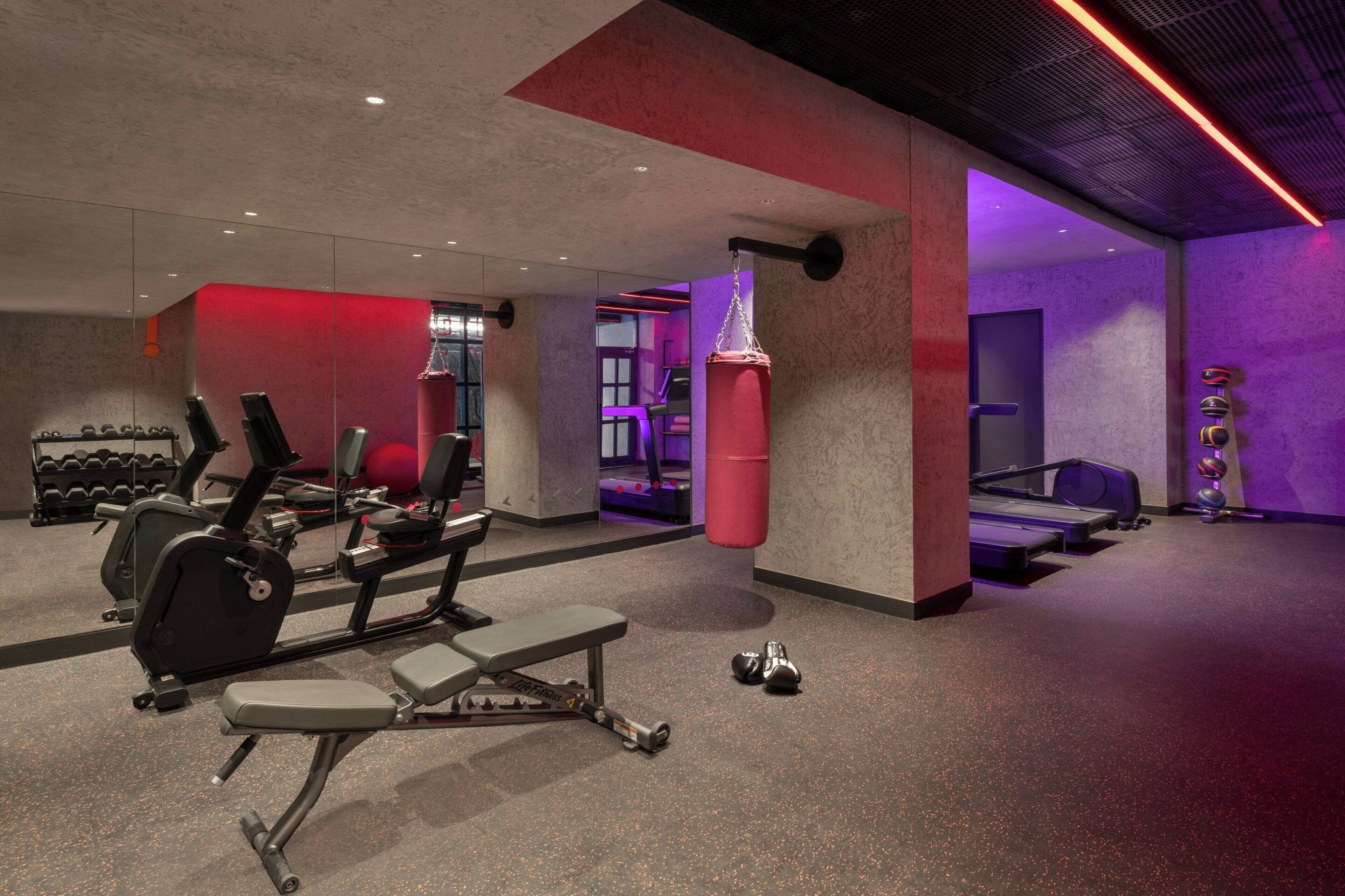 Een sportschool met trainingsapparatuur, een bokszak en een loopband.