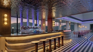 A bar area with stools, a bar counter, and a view of the mountains. - Moxy Kathmandu (Kathmandu)