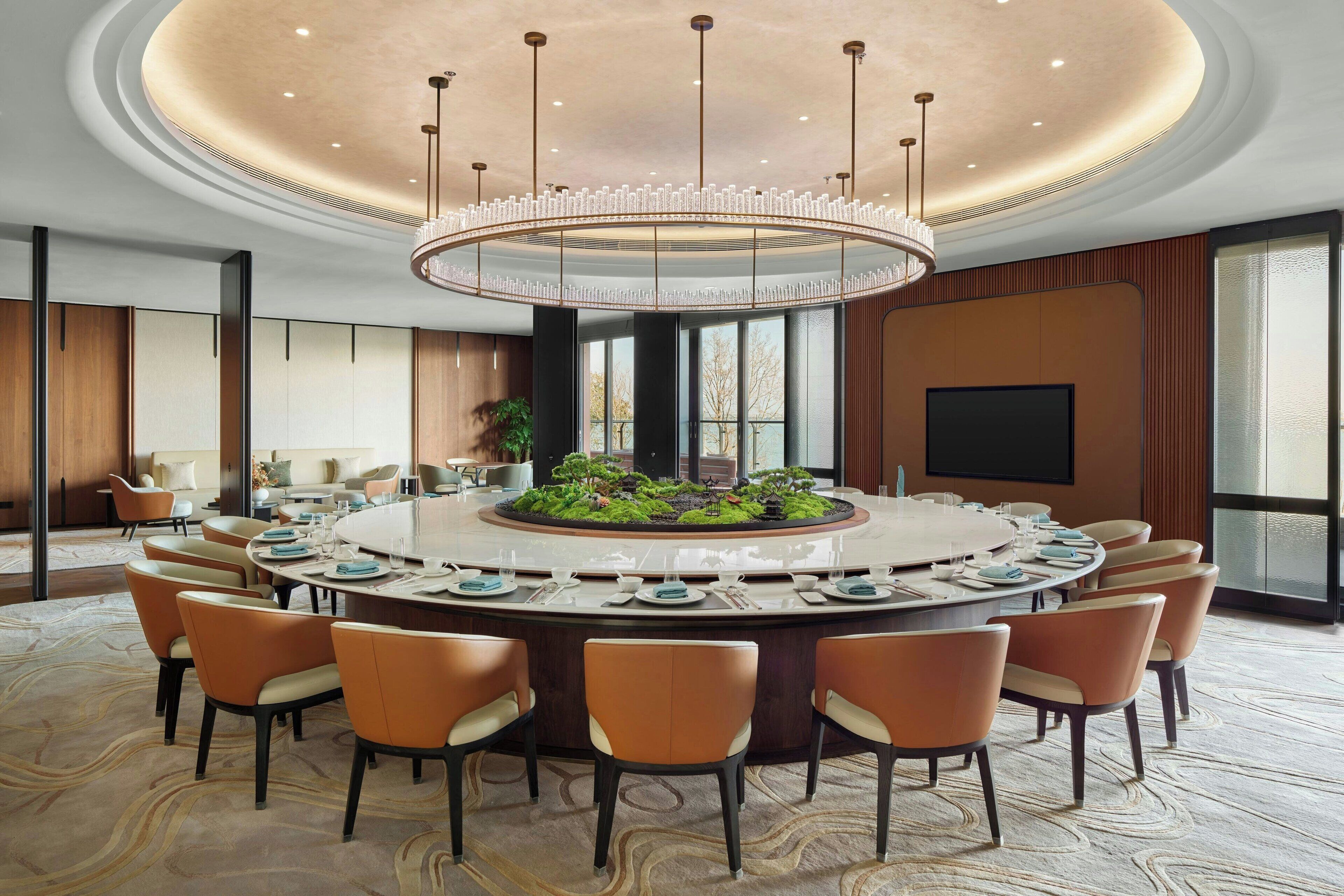 A modern conference room with a central island, round table, and orange chairs.