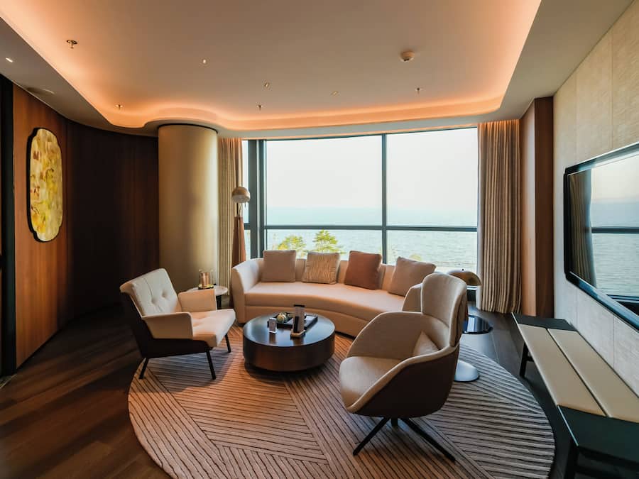 Un salon moderne avec un canapé aux lignes courbes, une table basse et une grande fenêtre donnant sur la mer.