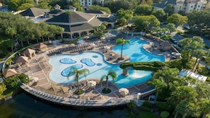 Un resort con una piscina central grande, varias piscinas más pequeñas y un puente que conecta diferentes zonas.