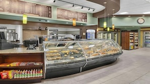Mostrador de panadería con diversos productos horneados y una zona de cafetería con un menú.