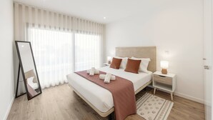 Un dormitorio moderno con una cama grande, una mesita de noche con lámpara y un espejo.