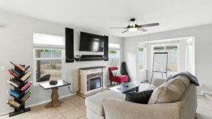 Ein Wohnzimmer mit Kamin, Fernseher, Bücherregal und einer Couch.