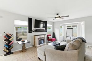 A living room with a fireplace, a TV, a bookshelf, and a couch. - Quiet & Safe Single Family Home Near Desert Ridge (Phoenix)