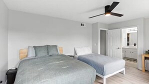 Ein Schlafzimmer mit zwei Betten, einem Deckenventilator, einem Kleiderschrank und einem kleinen Tisch.