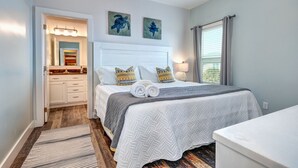 A bedroom with a bed, a nightstand, a lamp, and artwork on the wall. - Good Gulf Times · New Listing! Heated Pool, Hot Tub & Steps to Beach (Gulf Shores)