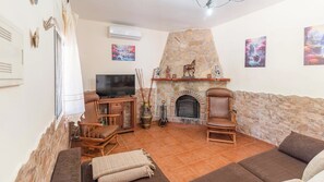 Ein Wohnzimmer mit Kamin aus Stein, einem Fernseher und zwei Holzsesseln.