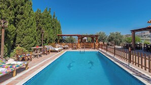 Une piscine avec des chaises longues et une pergola en bois.