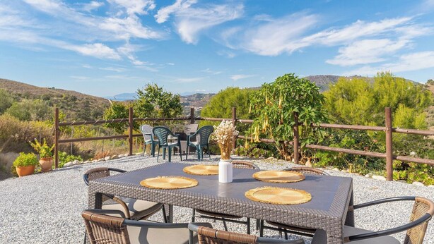 An outdoor patio with a table and chairs, surrounded by a wooden fence, overlooking a hilly landscape. - El Ranchito Torrox by Ruralidays (Málaga)