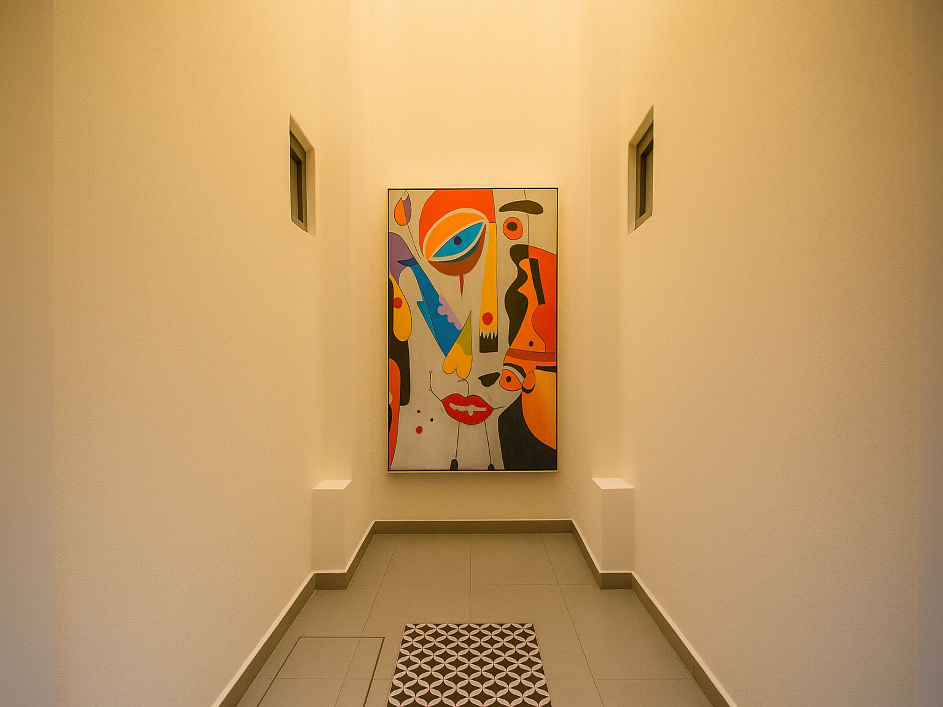 A hallway with a colorful abstract painting on the wall, a patterned floor, and a vent on the ceiling.