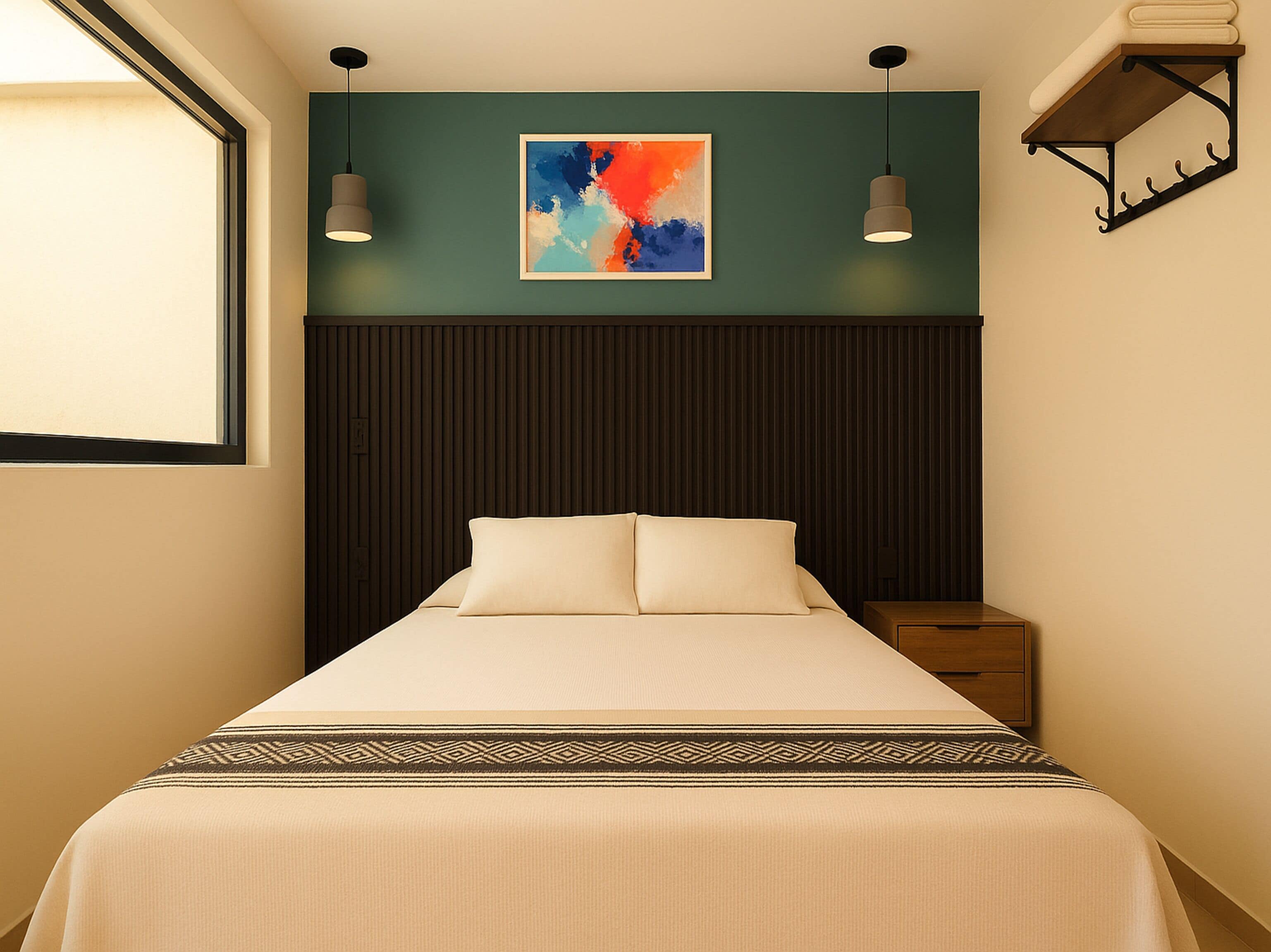 A neatly made bed with a patterned bedspread, a wall-mounted artwork, and a bedside table with a lamp.