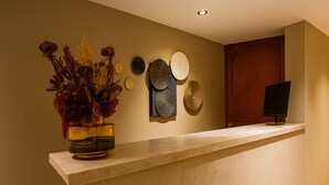 Un espace d’accueil avec un bureau en bois, un vase contenant des fleurs séchées et des assiettes décoratives accrochées au mur.