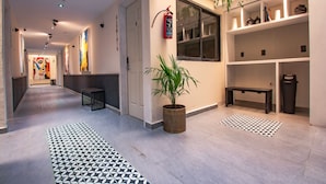 Un couloir moderne avec un sol à motifs, une plante en pot et des œuvres d’art accrochées aux murs.
