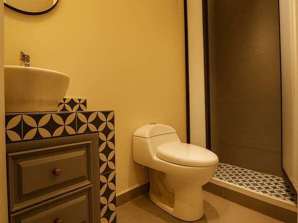A bathroom with a toilet, sink, and shower area.
