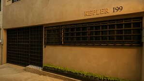 Une façade d’immeuble portant l’inscription « KEPLER 199 », et une rangée de plantes en pot le long de la base.