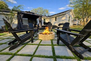 An outdoor patio with a fire pit, black lounge chairs, and a covered seating area. - Retro Style / Walk to Rangers / AT&T Stadium / Hot Tub (Arlington)