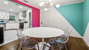 A modern kitchen with white cabinets, a pink accent wall, and a teal accent wall. - Retro Style / Walk to Rangers / AT&T Stadium / Hot Tub (Arlington)
