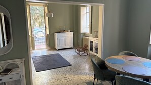 A room with a checkered floor, a round table with chairs, a white cabinet, and a rocking chair. - Guest House Foschi - Cozy Home in a Medieval Village (Castiglion Fosco)