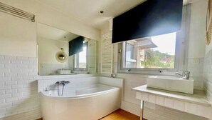 Een moderne badkamer met een vrijstaand bad, een wastafelmeubel en een grote spiegel.
