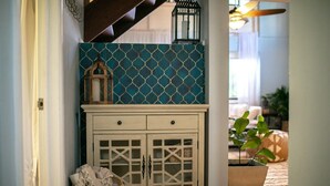Um corredor com um armário branco com portas de vidro e parede estampada em azul.