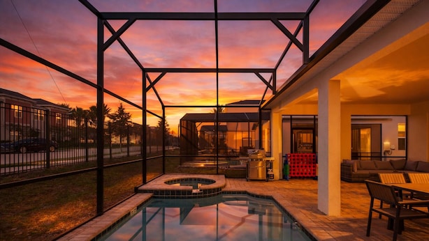 A swimming pool with a hot tub, outdoor seating, and a covered patio area. - New Welcoming Resort Home w/ Private Pool, sleeps 20 (Kissimmee)