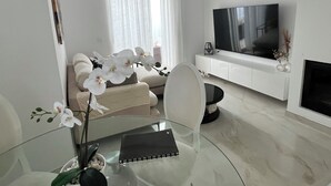 A modern living room with a glass dining table, a sofa, a TV, and a fireplace. - Luxury Villa with Private Pool in a Quiet Setting (Mazarrón)
