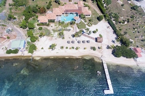 Luftaufnahme eines Anwesens an der Küste mit Schwimmbad, Strand und einer Anlegestelle.