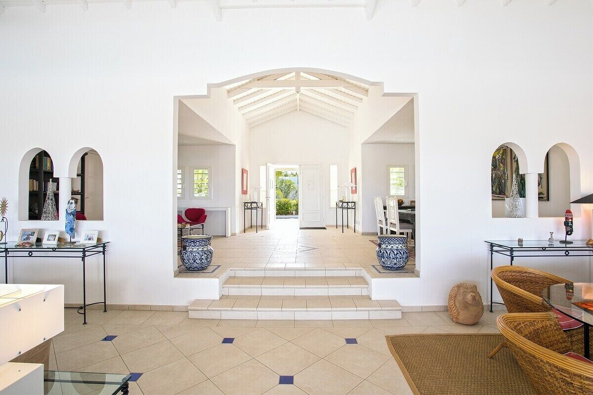 A spacious interior with a central staircase leading to an open area, white walls, and a tiled floor.