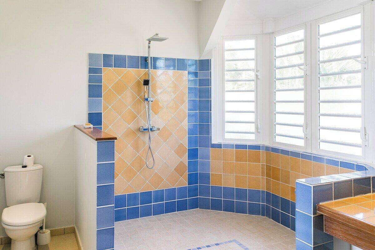Un bagno con doccia, servizi igienici e una finestra con persiane.