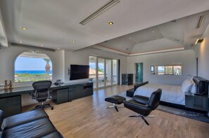 A spacious bedroom with a large bed, a desk, and a television. - Sandyline   Private Paradise   Resort Style Villa (Saint Martin)