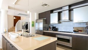 Een moderne keuken met een centraal eiland, roestvrijstalen apparatuur en een groot raam.