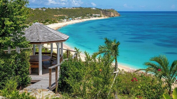 A gazebo with a wooden deck overlooking a beach with clear turquoise waters and a distant hill with buildings. - Libellule   Elevated Beachfront Villa (Saint Martin)