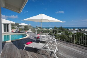 A wooden deck with a pool, white sun loungers, and umbrellas. - Ocean View   Stunning Orient Bay Villa (Saint Martin)