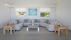 Ein modernes Wohnzimmer mit einem grauen Ecksofa, zwei Holznachttischen, einem Couchtisch in der Mitte und einem großen abstrakten Gemälde an der Wand.