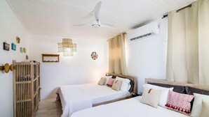 A bedroom with two beds, a ceiling fan, a wooden wardrobe, and a wall-mounted air conditioner. - Mary's Beach Cottage: Seashore (Saint Martin)