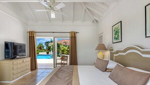 Ein Hotelzimmer mit Bett, Fernseher, Lampe und Blick auf einen Pool.