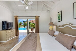 Ein Hotelzimmer mit Bett, Fernseher, Lampe und Blick auf einen Pool.