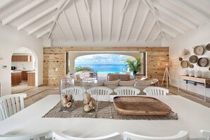 A modern interior with a dining area, white furniture, and a view of the sea. - Happy Bay   Classic French Creole Villa   Stunning Views (Saint Martin)