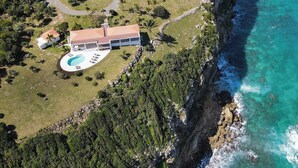 An aerial view of a coastal property with a large house, a swimming pool, and lush greenery. - Falaise des Oiseaux   Clifftop villa with Stunning Views (Saint Martin)