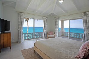 Ein Schlafzimmer mit einem großen Bett, einem Fernseher und Meerblick.