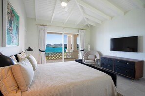 Ein Schlafzimmer mit einem großen Bett, einem Fernseher, einem Sessel und Meerblick.