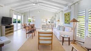 A spacious living area with a high ceiling, a television, seating arrangements, and a view through large windows. - Falaise des Oiseaux   Clifftop villa with Stunning Views (Saint Martin)