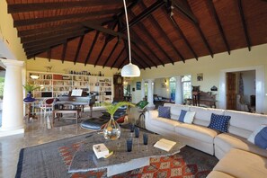 A spacious living room with a high ceiling, a piano, a sofa, and a bookshelf. - Les Zephyr's   West Indian Style Villa   Stunning Views (Saint Martin)