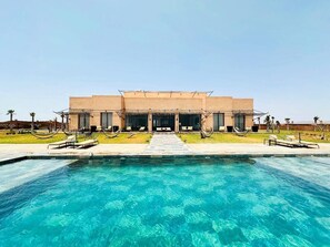A modern hotel with a swimming pool, outdoor seating, and a clear view of the pool area. - Luxury villa with heated pool - Private Foot & Padel - Marrakech (Ouled boudden)