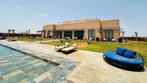 Un bâtiment moderne doté d’une piscine, d’un espace extérieur aménagé et offrant une vue sur un ciel dégagé.
